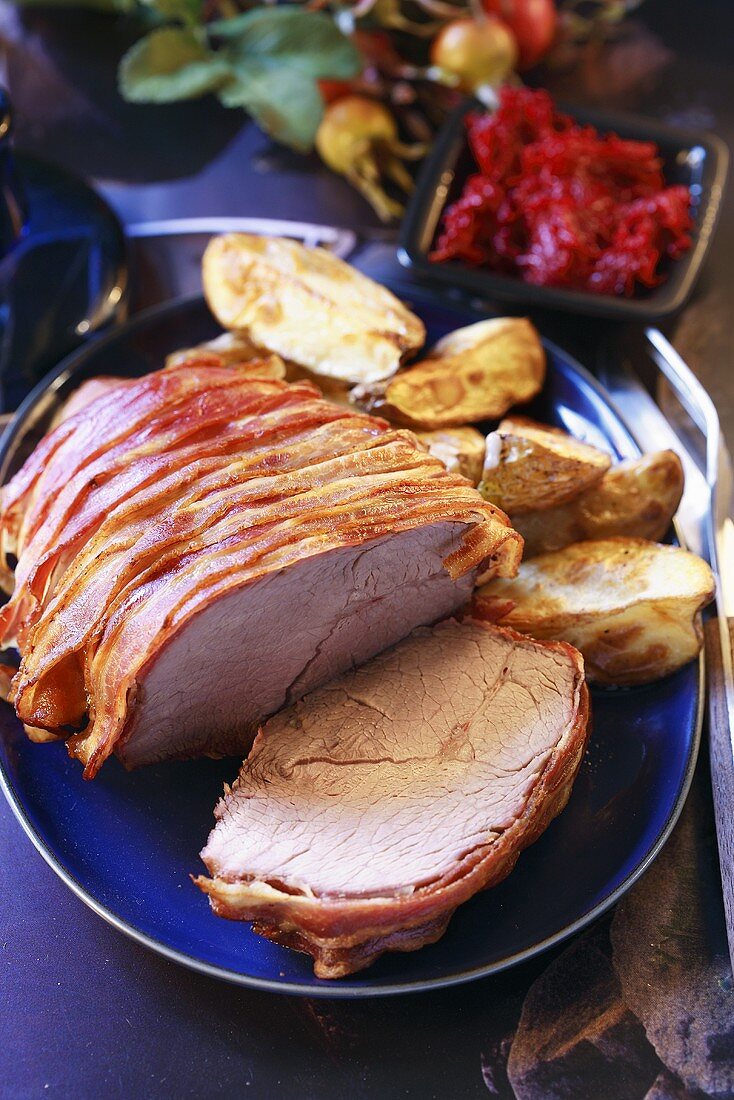 Roast beef wrapped in prosciutto, roast potatoes, red cabbage