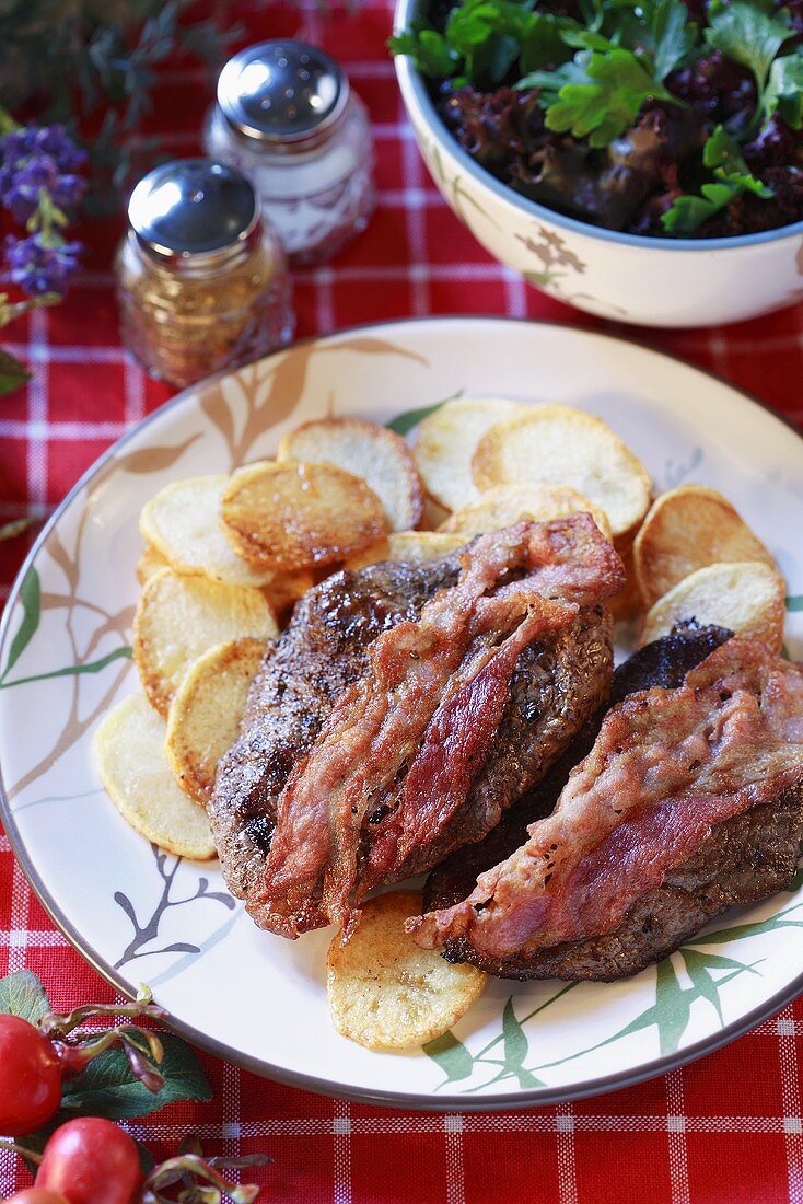 Beefsteaks with bacon and fried potato slices