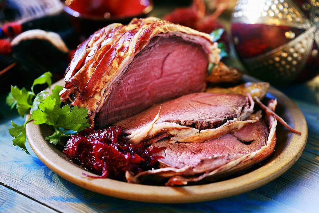 Bacon-wrapped roast beef, partly carved