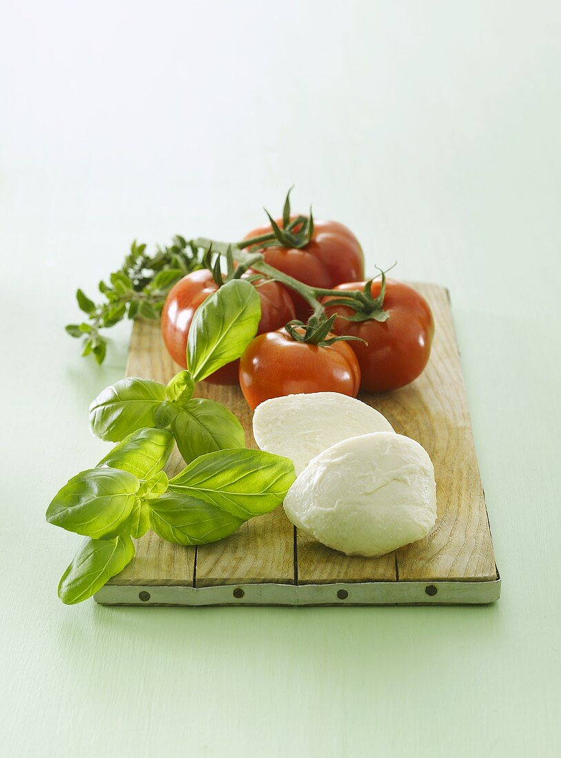 Tomatoes, basil and mozzarella on chopping board