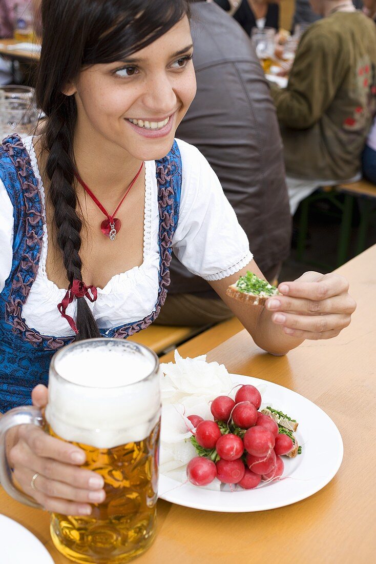 Frau mit Brotzeit und Bier am Biertisch sitzend (Oktoberfest)