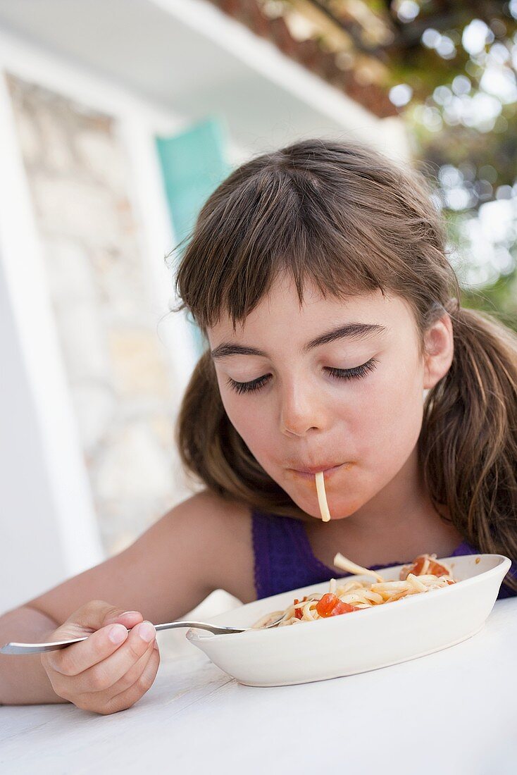 Mädchen saugt Spaghetti in den Mund
