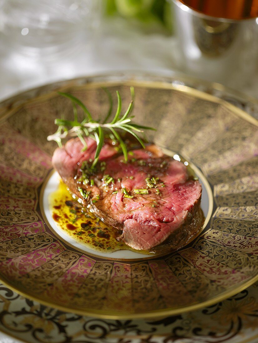 Eine Scheibe Roastbeef mit Olivenöl, Balsamico und Rosmarin