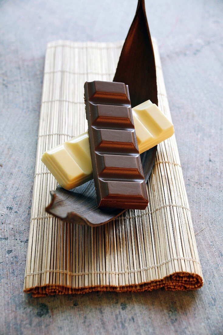 Schokoladenstücke von weisser und dunkler Schokolade auf Kakaofruchtschale