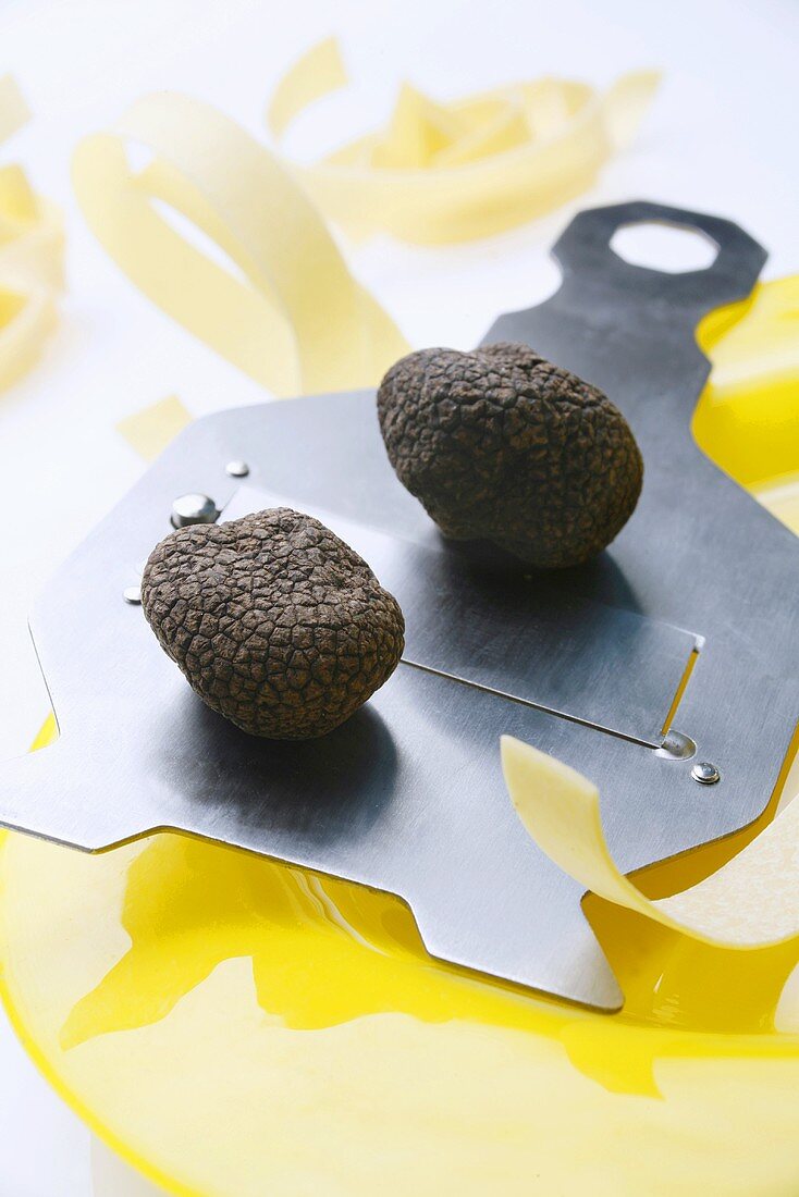 Black truffles (Chinese truffles) on truffle slicer, ribbon pasta