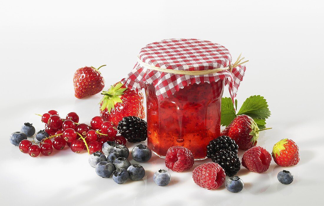 Berry jam in jar surrounded by fresh berries