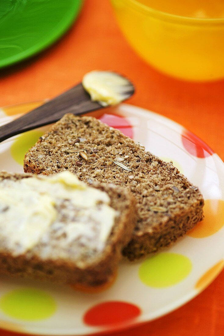 Slices of four-grain bread, one buttered