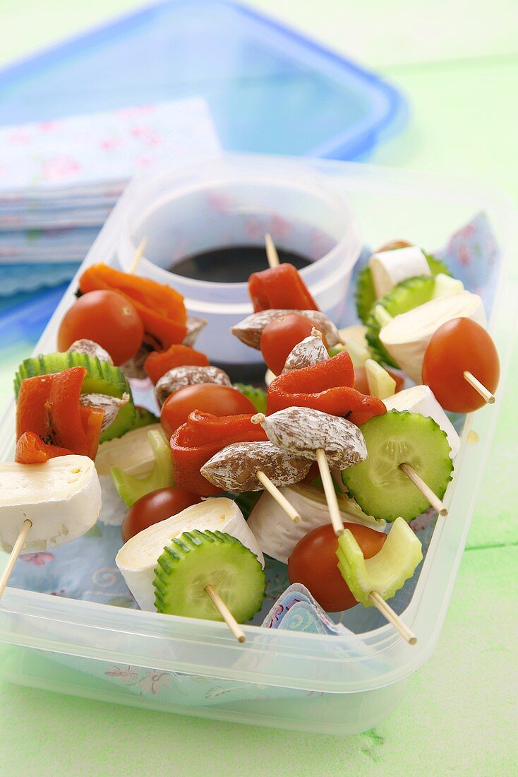 Vegetable, sausage and cheese skewers in a plastic box