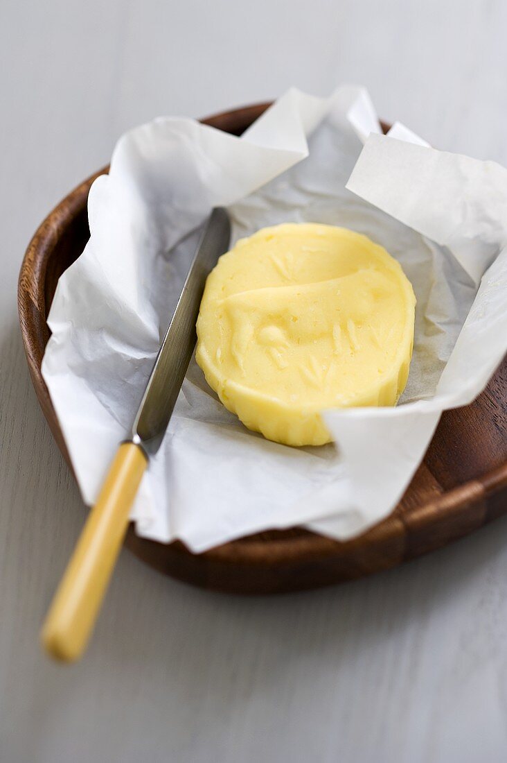 Ein Stück Butter in Papier mit einem Messer
