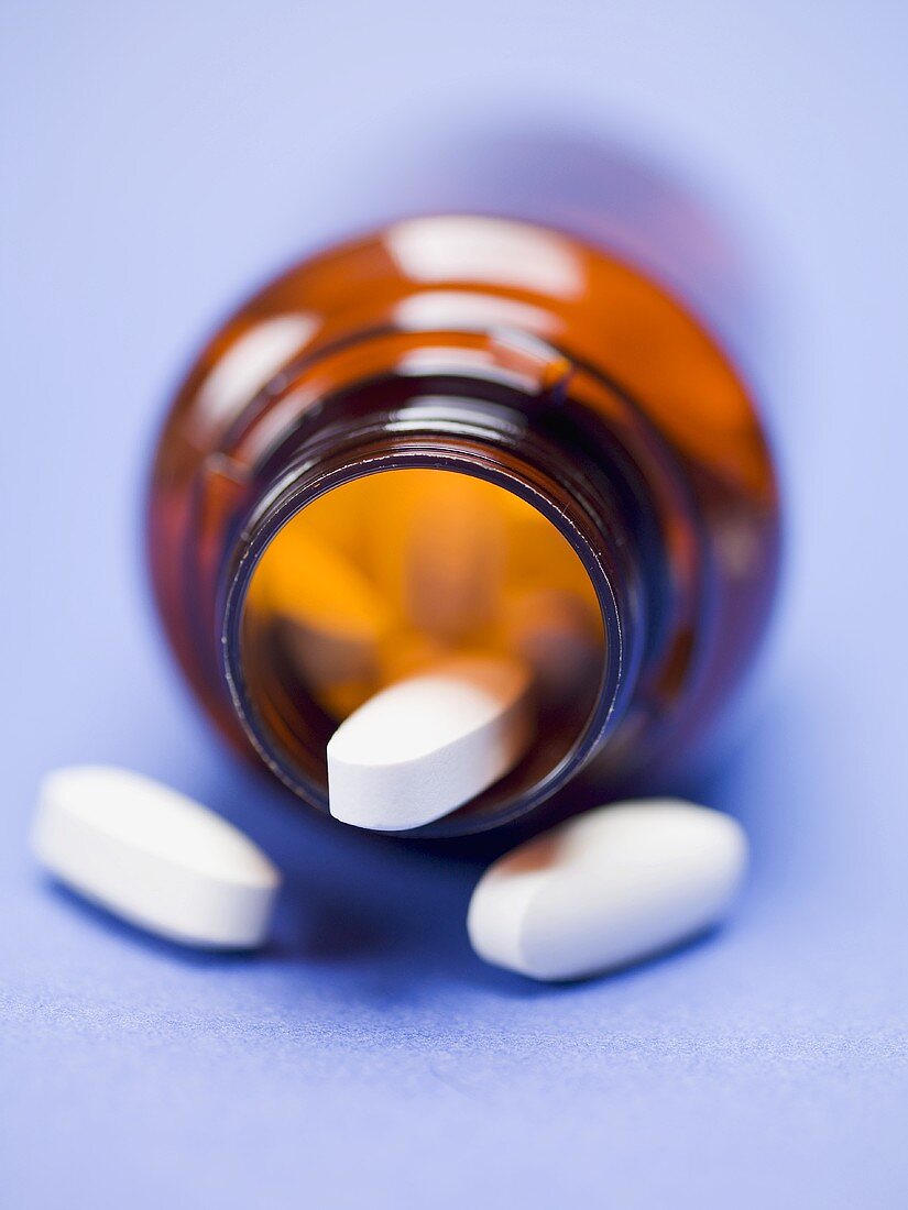 Tabletten im umgekippten Medizinglas (Close Up)