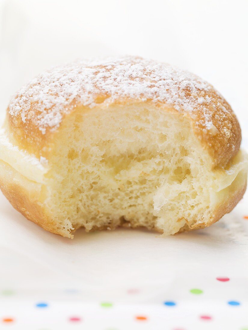 Doughnut dusted with icing sugar, a bite taken