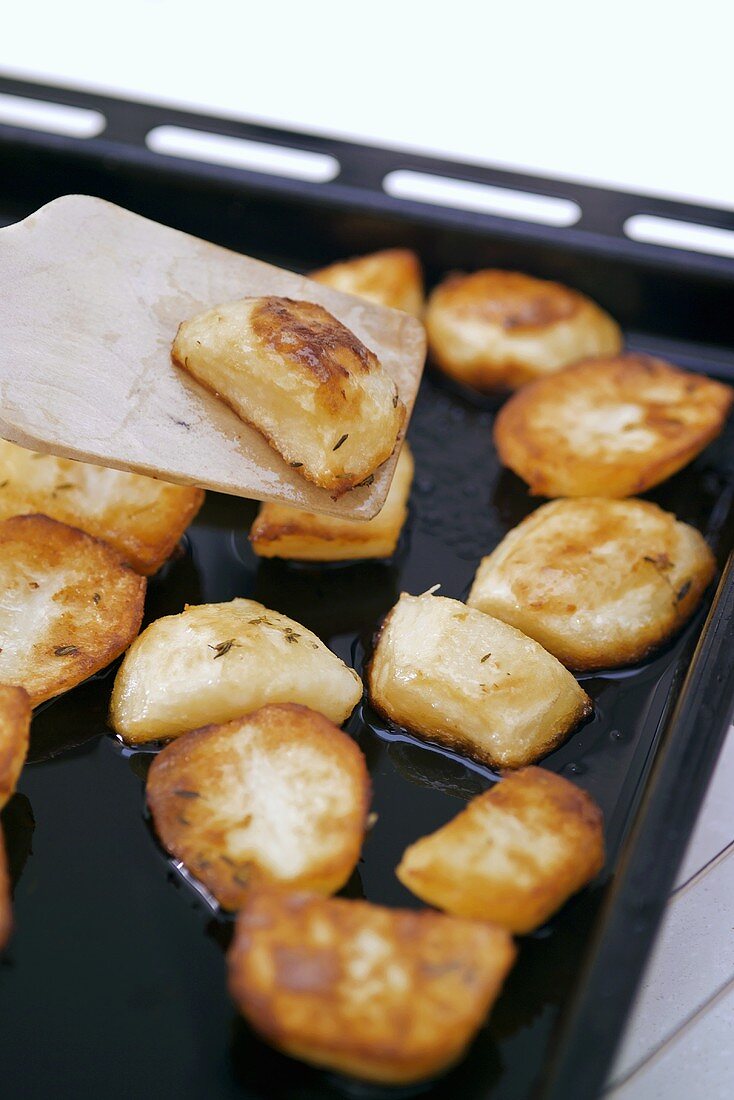Roast potatoes on baking tray with spatula