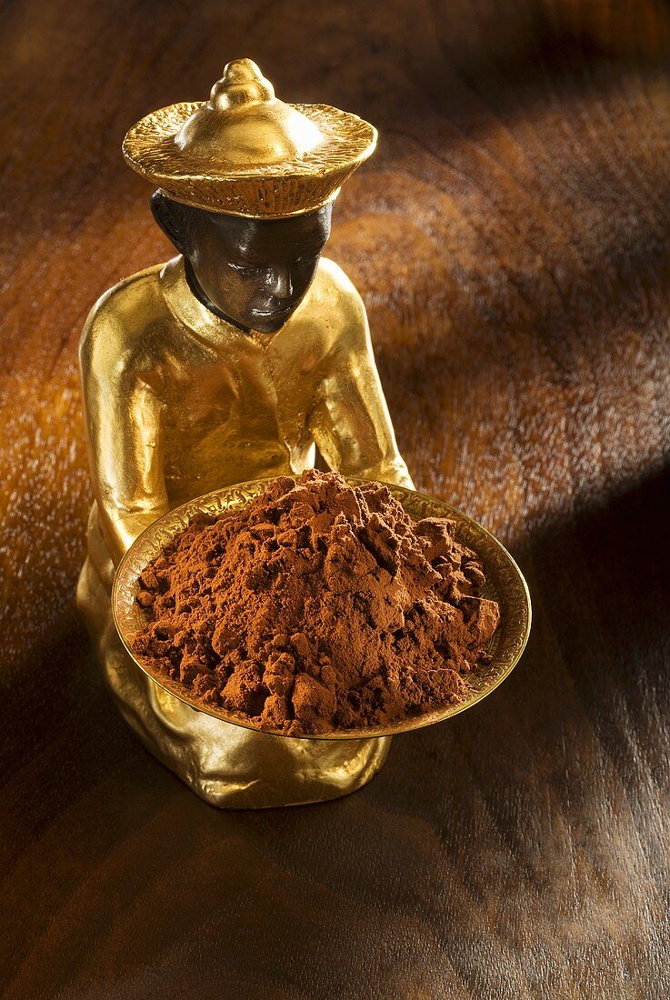 Gilded statuette with a bowl of cocoa powder