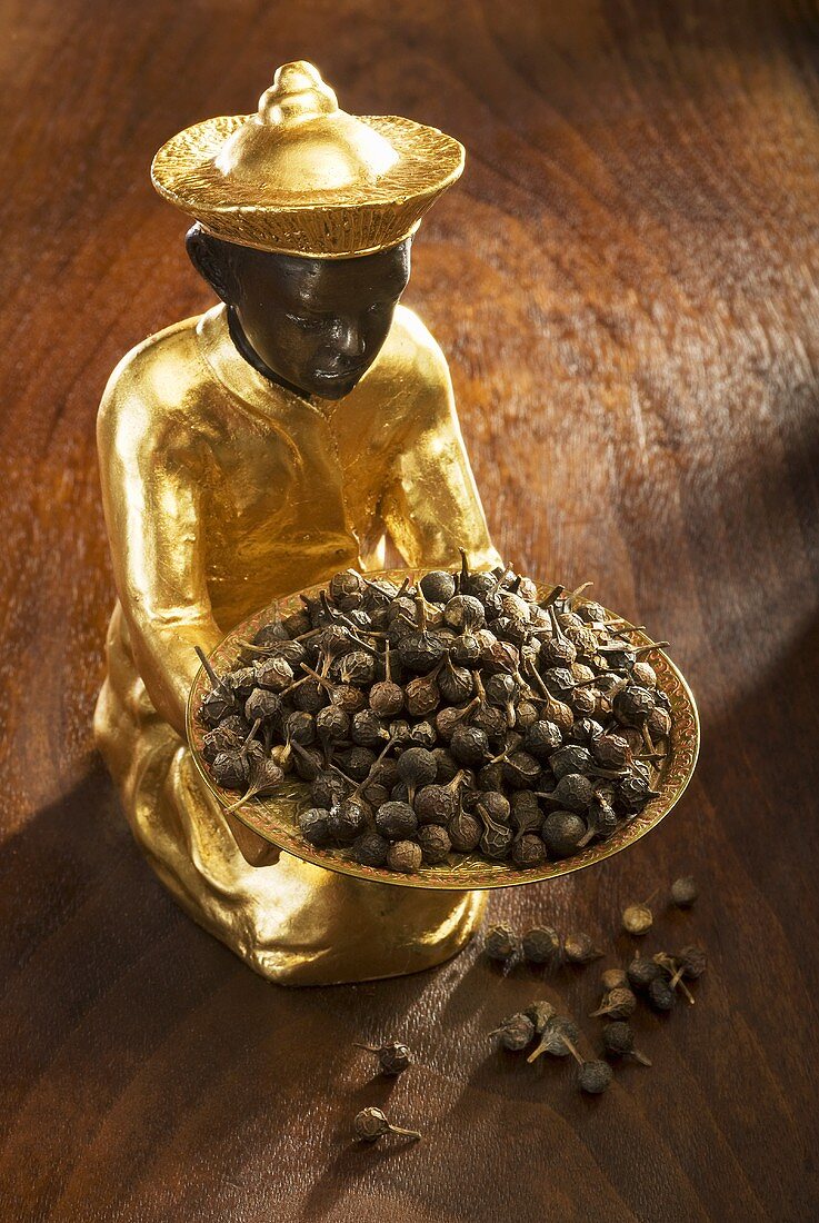 Gilded statuette with tailed pepper in and in front of bowl