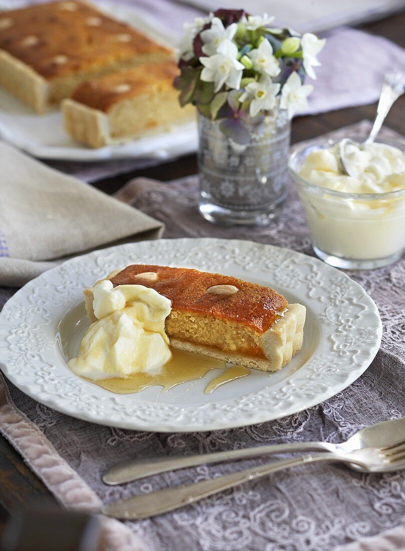 Almond cake with cream and honey, flowers in background
