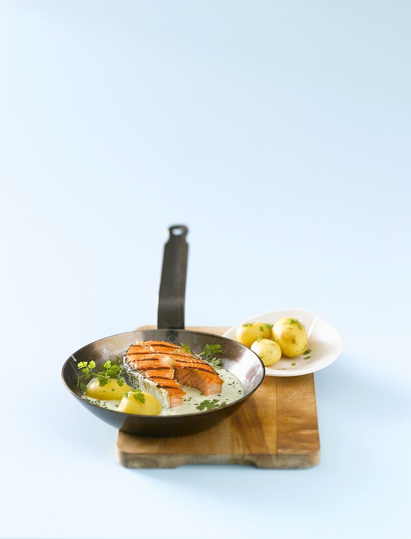 Salmon steak with herb sauce & potatoes in grill frying pan