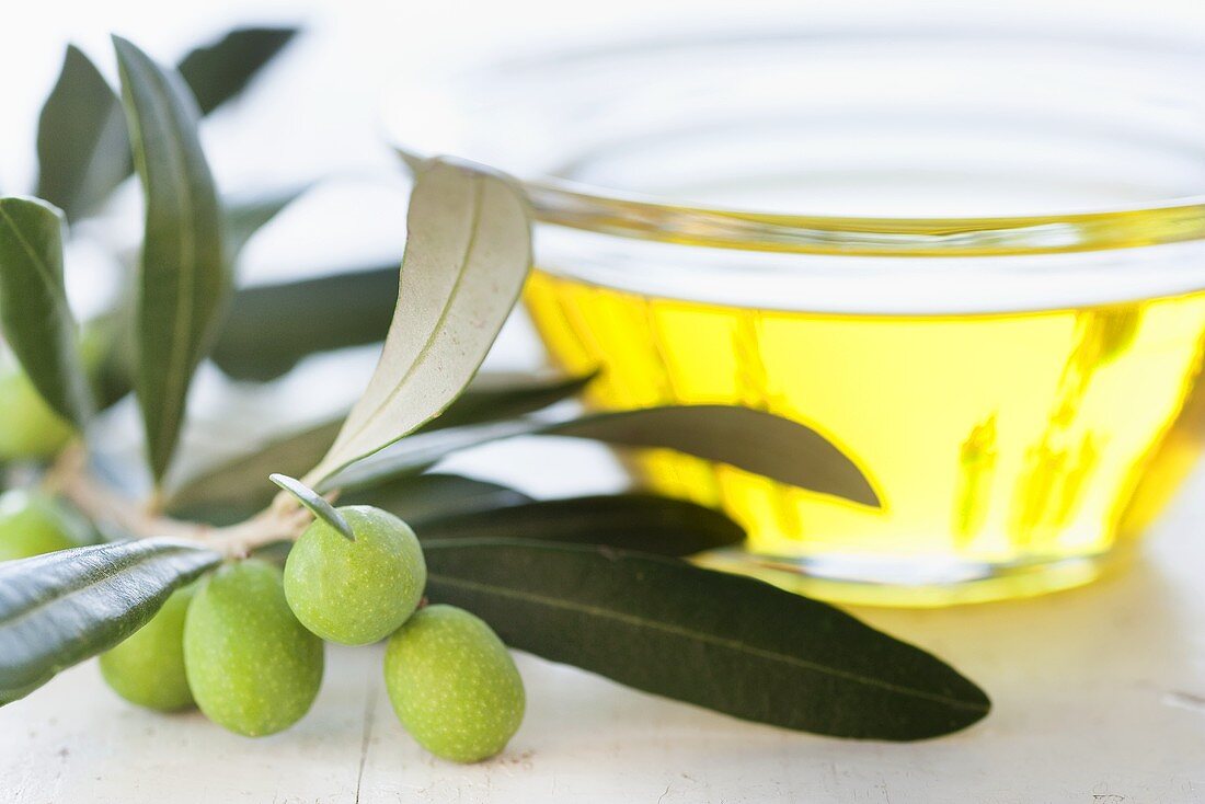 A small bowl of olive oil with an olive sprig