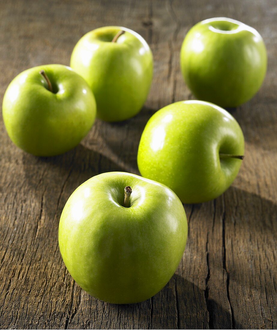 Fünf Granny Smith Äpfel auf Holzuntergrund