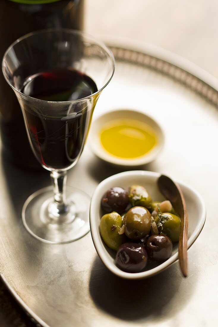 Marinierte Kalamata-Oliven, Olivenöl und Glas Rotwein