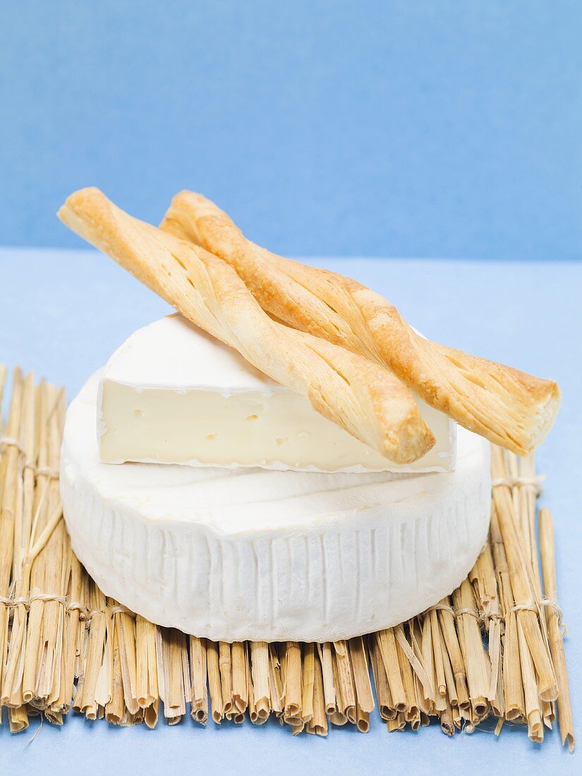 Camembert with savoury sticks on straw mat