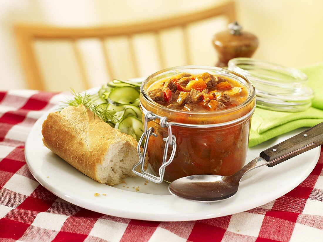 Goulash in jar with cucumber salad and baguette