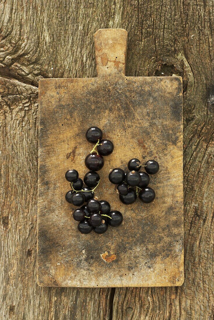 Schwarze Johannisbeeren auf altem Schneidebrett