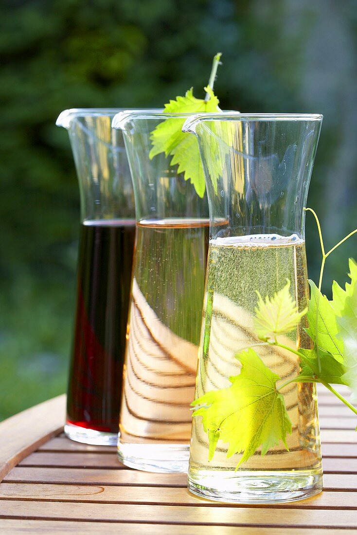 Wine in carafes on wooden table out of doors
