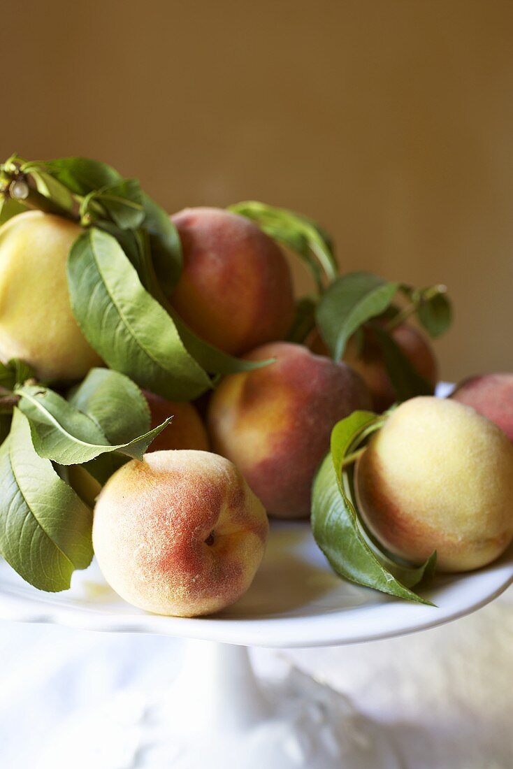 Several peaches on a cake stand