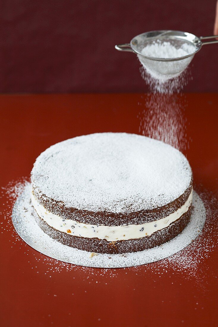 Dusting a cake with icing sugar