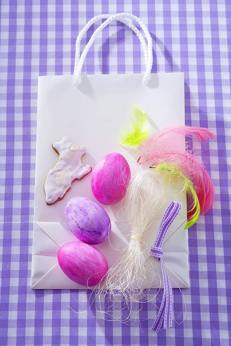 Ostereier, Osterhasen-Plätzchen & bunte Federn auf Papiertasche