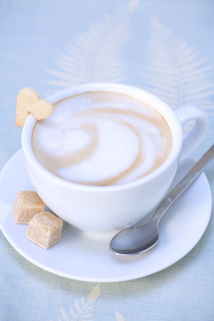 Cappuccino mit Herzkeks und Zuckerwürfeln