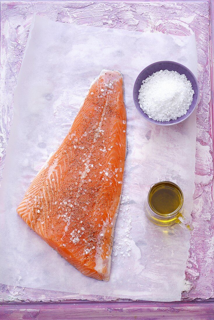 Salmon seasoned with salt, pepper & olive oil on baking parchment