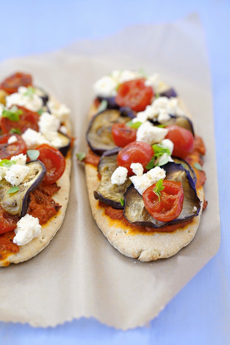 Zwei Mini-Pitabrotpizzen mit Auberginen, Kirschtomaten, Feta