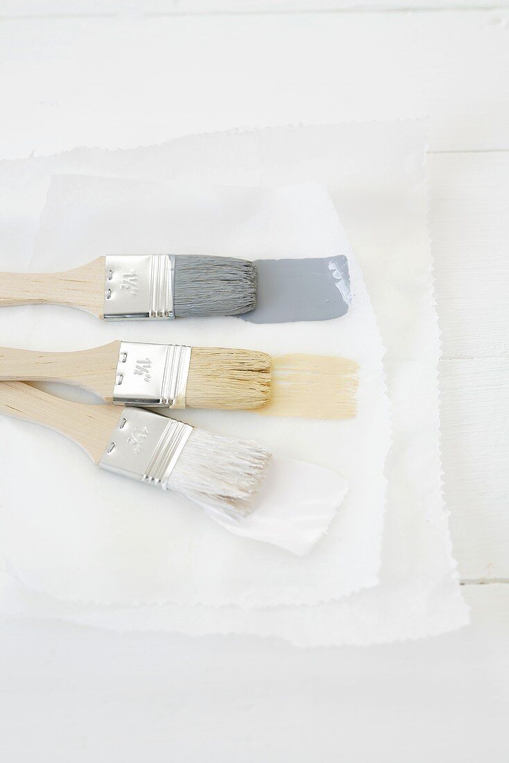 Paintbrushes with three different colours of paint on paper