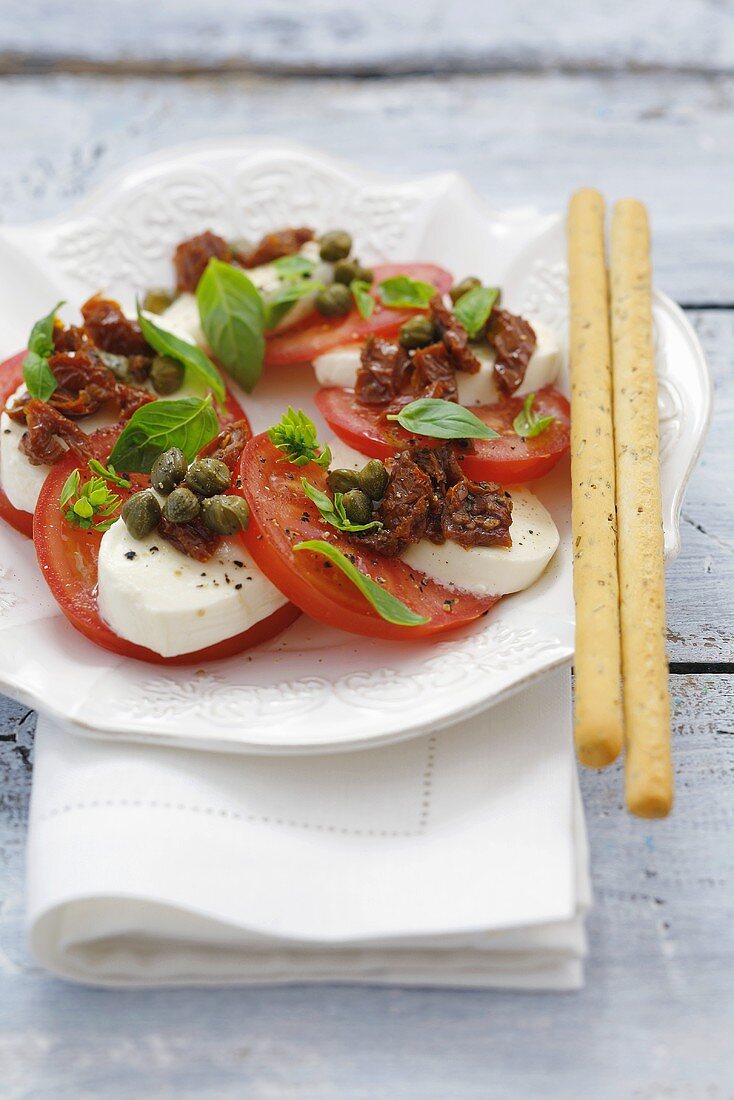 Tomate-Mozzarella mit getrockneten Tomaten, Kapern, Grissini
