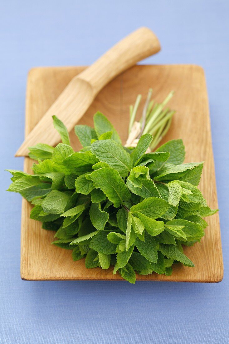 A bunch of fresh mint on a wooden board with wooden knife