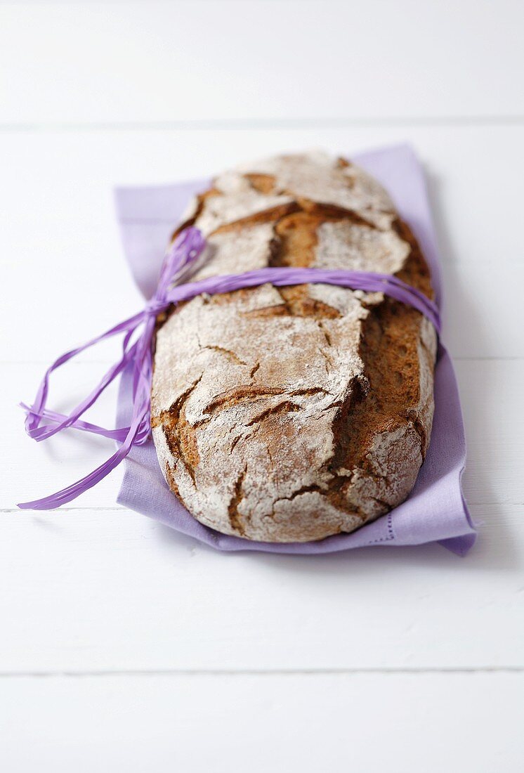 Wholemeal bread with ribbon on purple fabric napkin