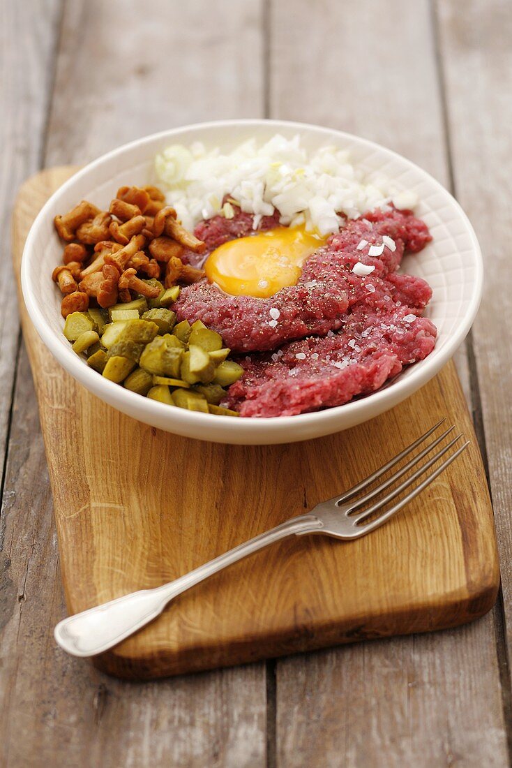 Steak tartare with egg, onions, chanterelles and gherkins