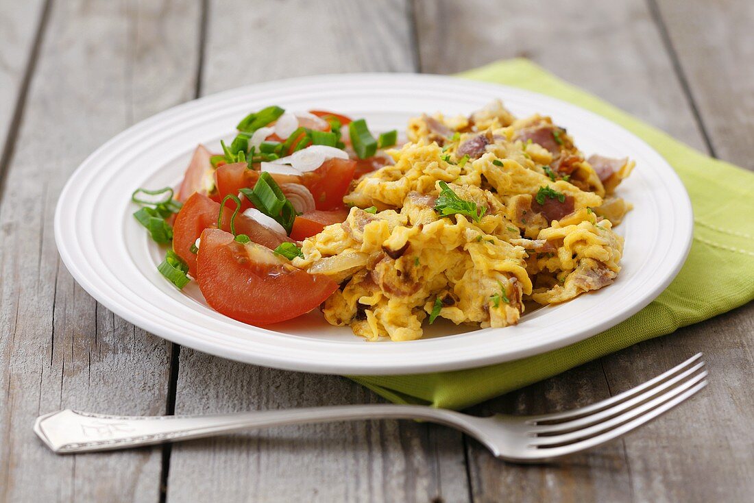 Scrambled egg with ham, parsley and tomato salad