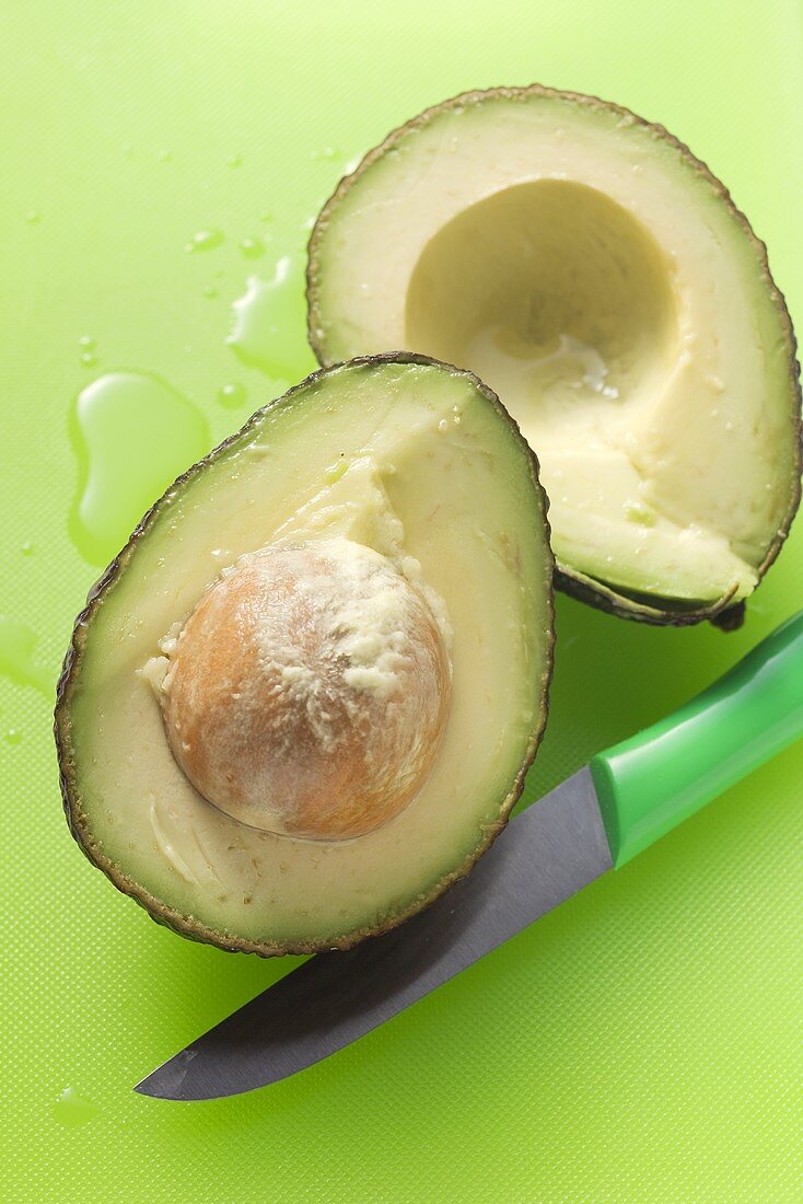 Halved avocado with knife