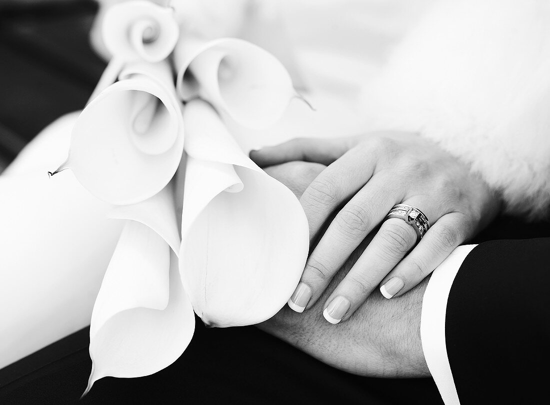 Bridal couple's hands with wedding bouquet