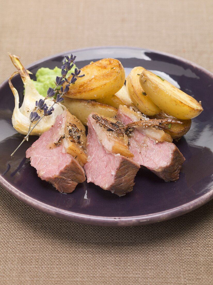Slices of roast lamb with roasted potatoes and garlic