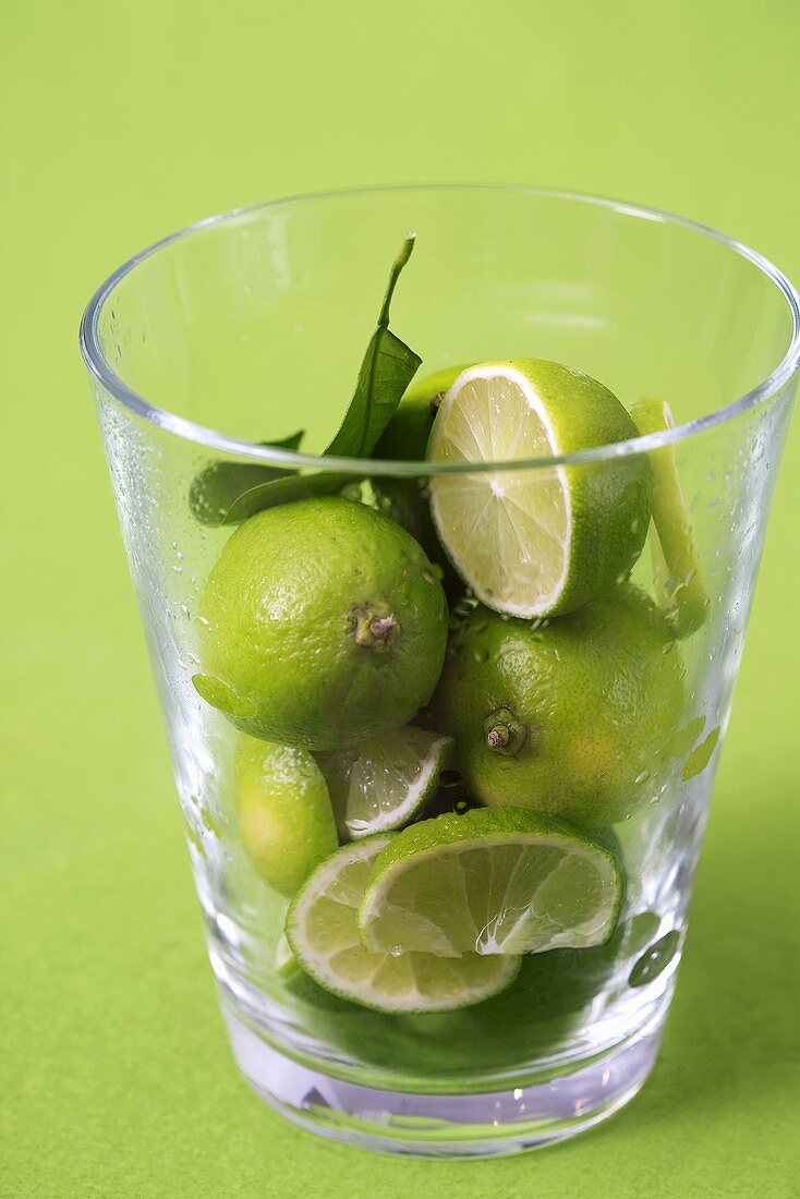 Ganze und geschnittene Limetten in einem Glas