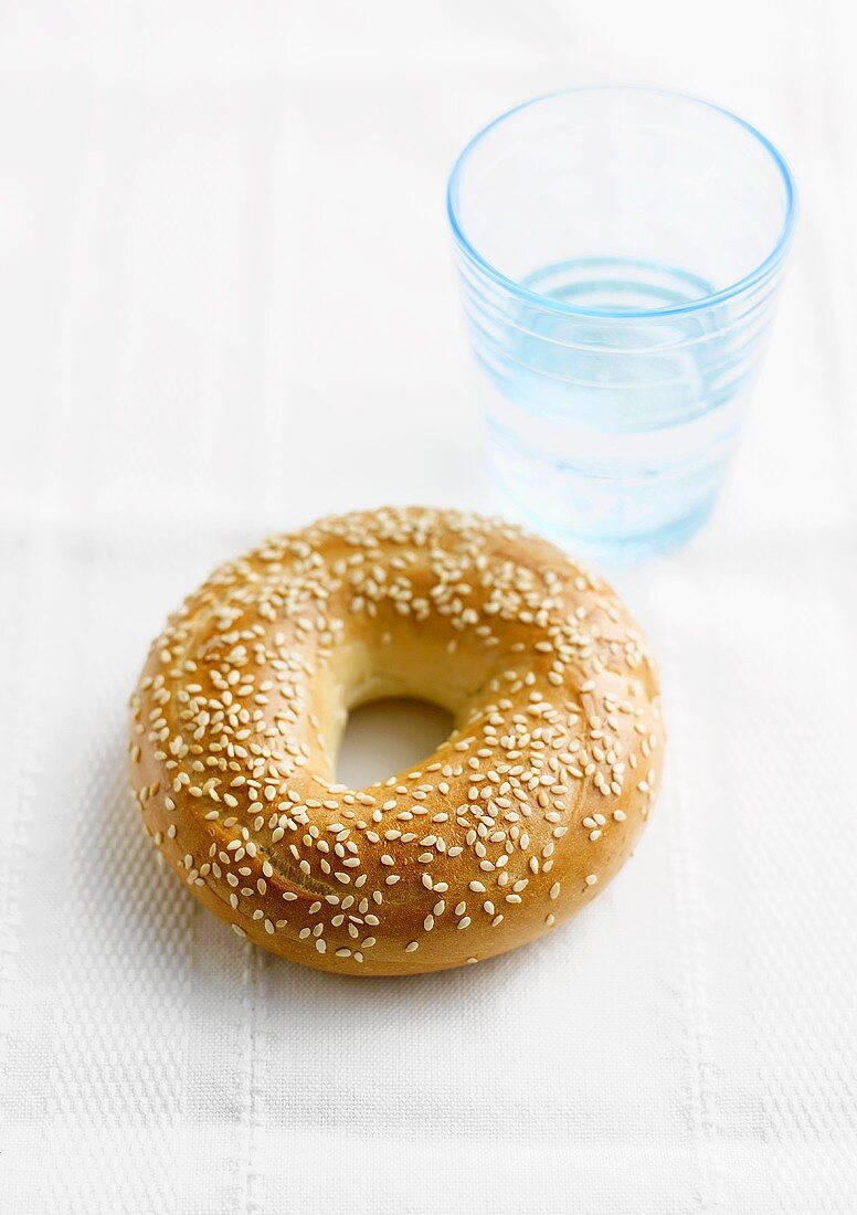 Sesame bagel with a glass of water