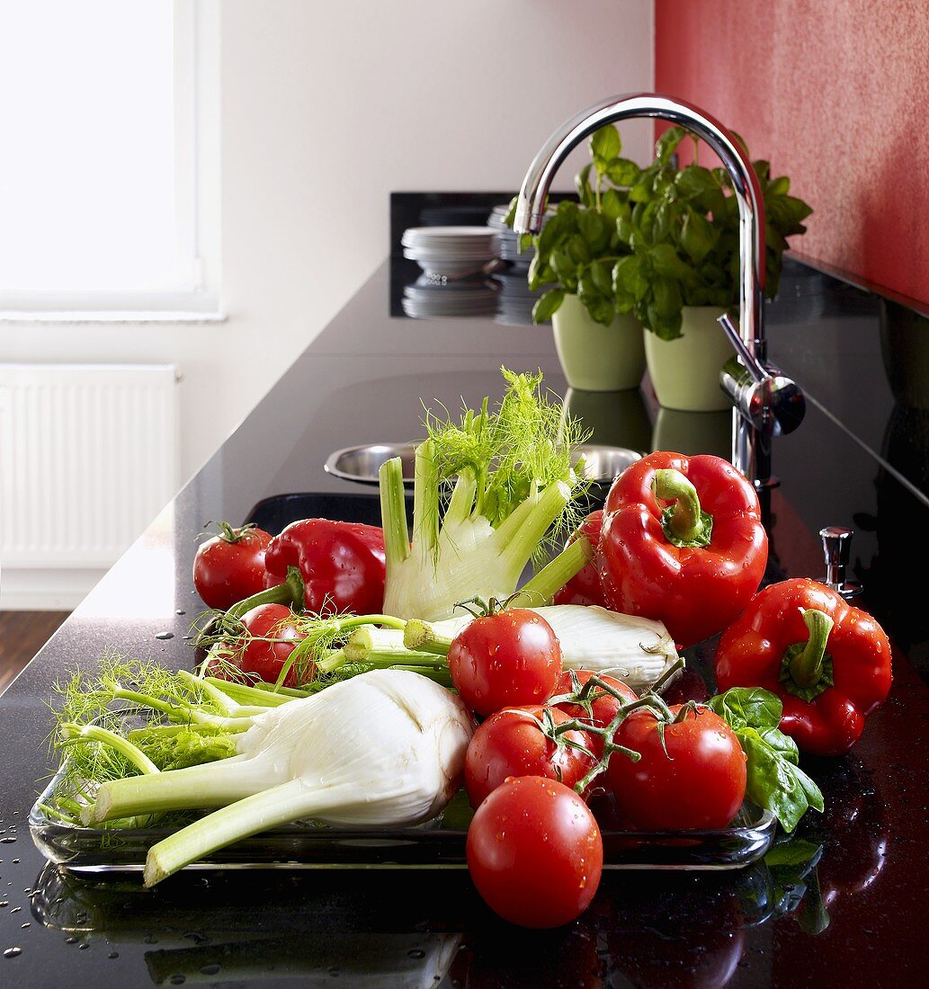 Fennel, tomatoes and peppers beside sink in kitchen