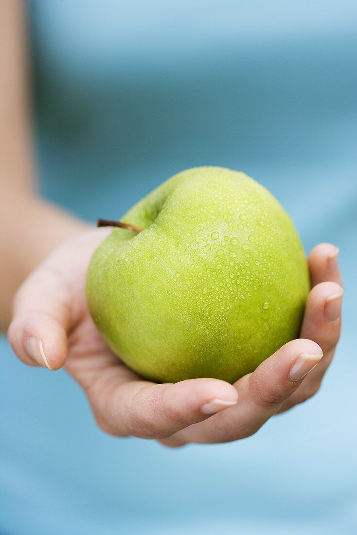 Hand hält grünen Apfel