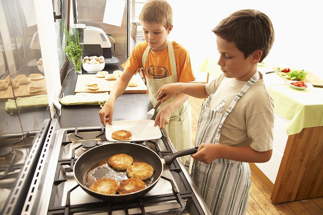 Two boys frying fish cakes