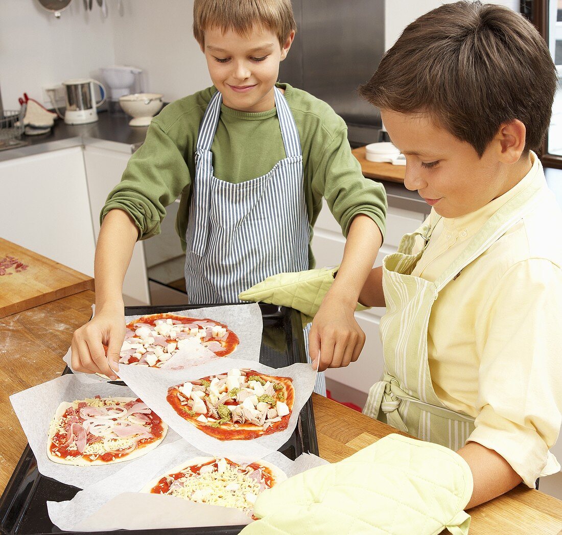 Two boys making pizzas