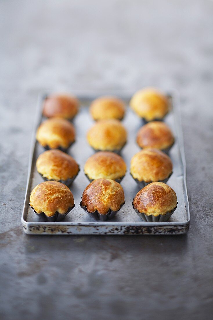 Brioches in small baking tins on a baking tray