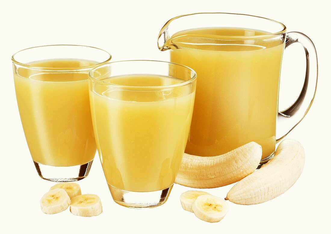 Banana juice in jug and two glasses and fresh banana